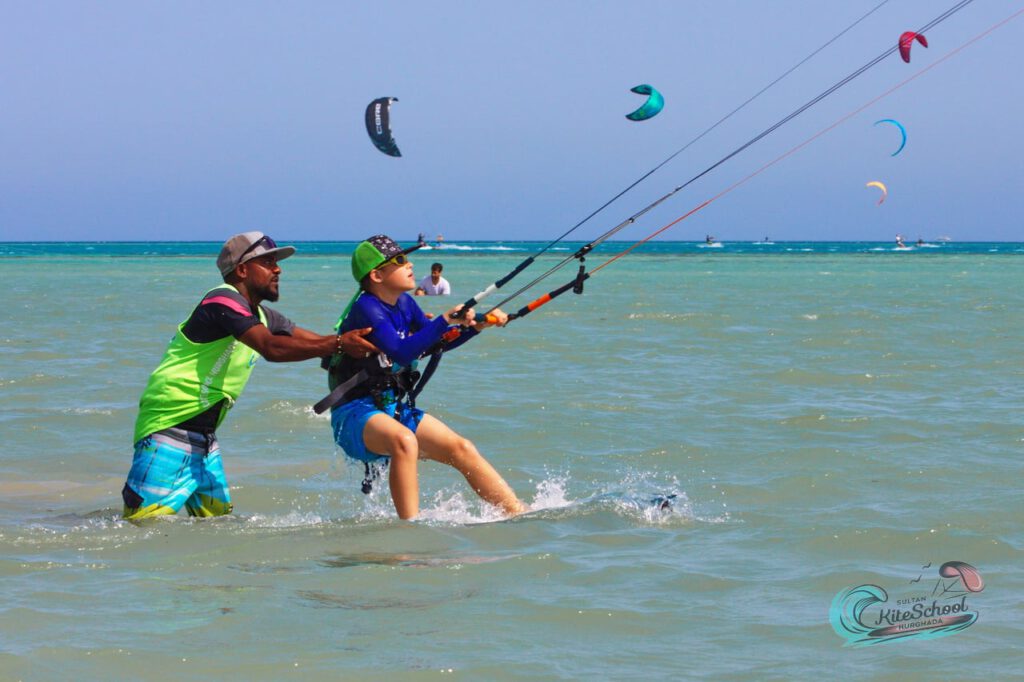 Instructor guiding a young student flying a kite during a kitesurfing lesson in Hurghada
