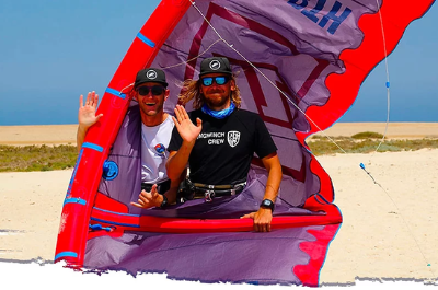 Two kite repairers holding up a repaired kite on the beach – kite repair service in Hurghada