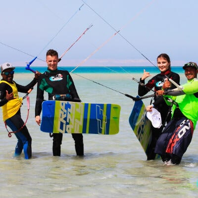 Kitesurfing students with boards and instructors in waist-deep water in Hurghada